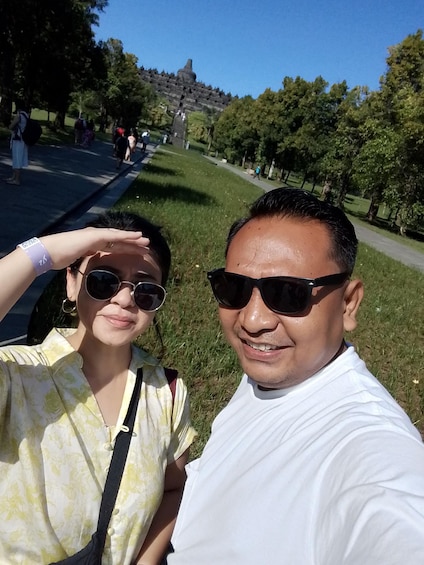 Kaksi ihmistä ottaa selfien puistossa, taustalla näkyy puita ja polku. 4