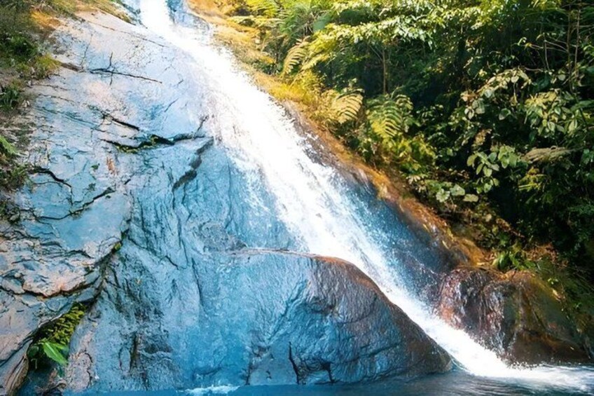 A waterfall cascading over a rocky cliff surrounded by lush greenery. 1