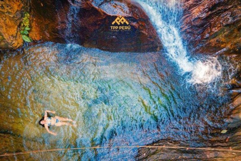 A person swimming in a river with a waterfall in the background. 4