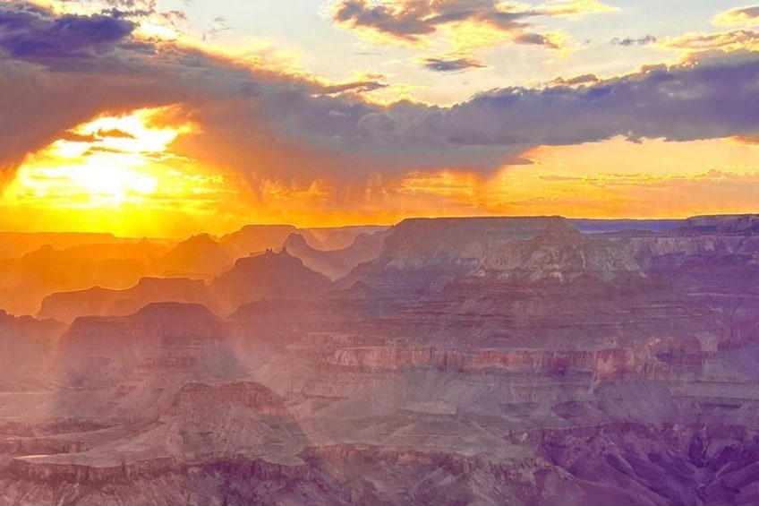 A canyon with layered rock formations and a sunset. 1