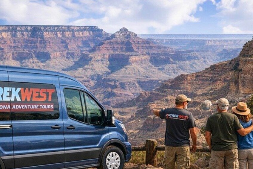 A blue van with 'REKWEST' and 'SONA ADVENTURE TOURS' on the side parked on a mountain overlooking a canyon. 3