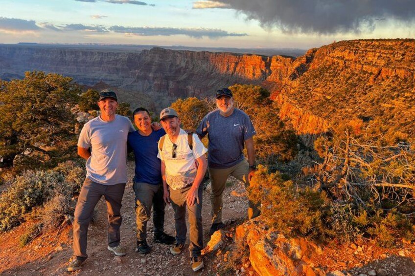 Four people standing on a rocky outcrop with a canyon in the background. 5