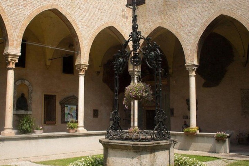 An architectural courtyard with arches, a central fountain, and potted plants. 2