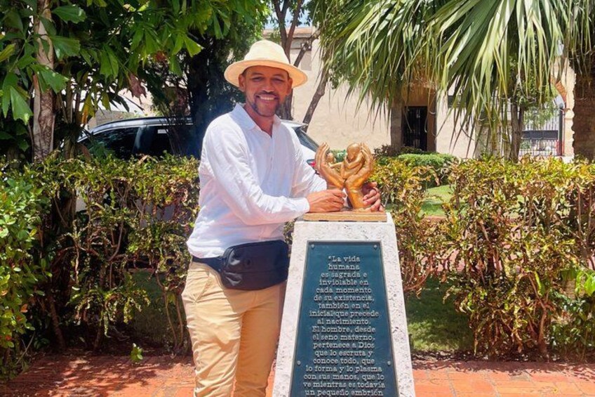 A person holding a trophy in front of a plaque with text. 1