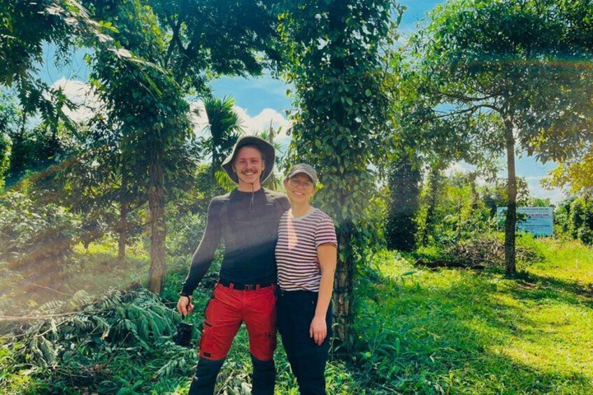Two people standing in a forested area with trees and greenery. 4