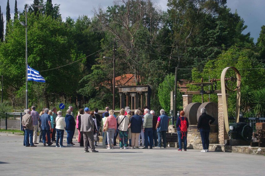 A group of people standing in a line, a flag, and a historical structure. 3