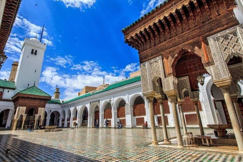 A courtyard with arches, a tower, and a tiled floor. 2