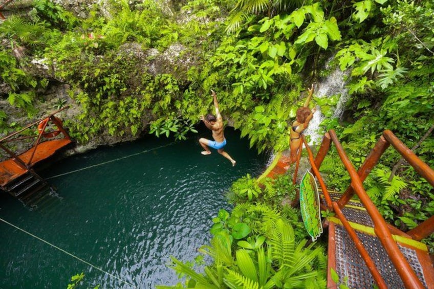 A person jumping into a pool from a wooden bridge surrounded by lush greenery. 4