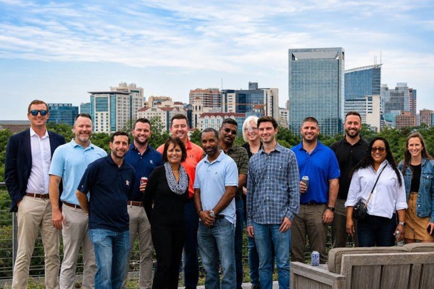 A group of people standing on a rooftop with a city skyline in the background. 3