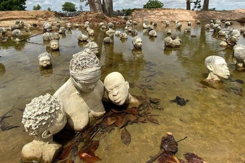 A pond with numerous stone sculptures of human heads. 5