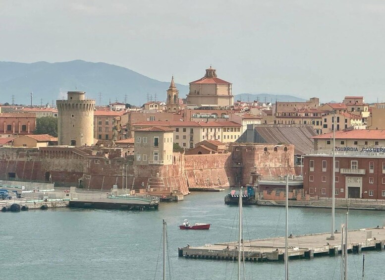 A coastal cityscape with historic buildings, a prominent tower, and a calm harbor with boats. 5