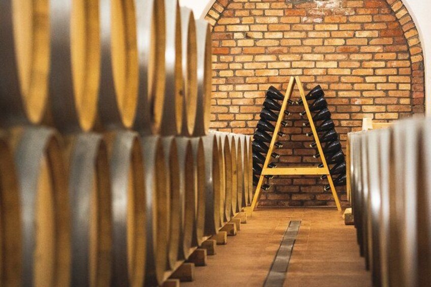 A wine cellar with rows of wine barrels and a wooden rack in the center. 4