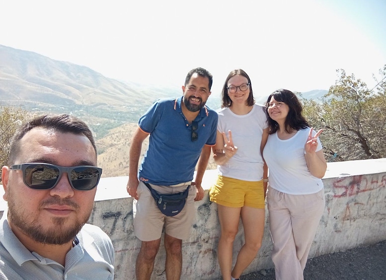 Un groupe de personnes se tient sur une corniche, avec un paysage montagneux en arrière-plan. 3