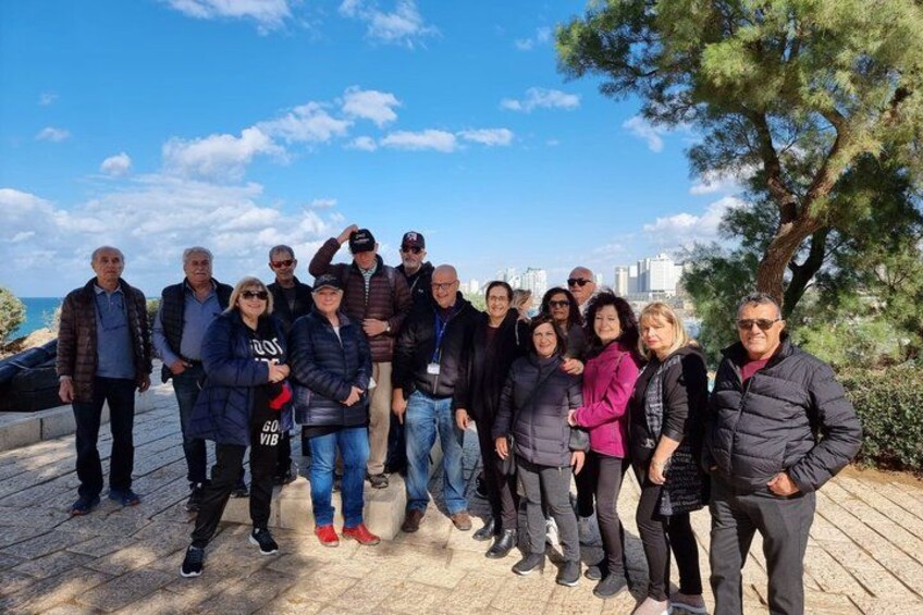 A group of people standing on a paved area with a body of water and a city skyline in the background. 5