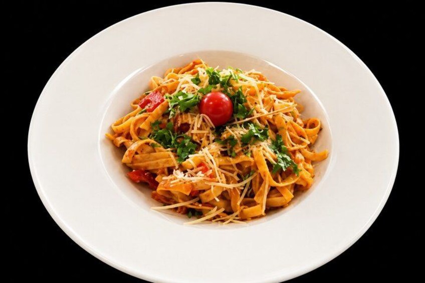 A plate of pasta with tomatoes, cheese, and a cherry tomato garnish. 3