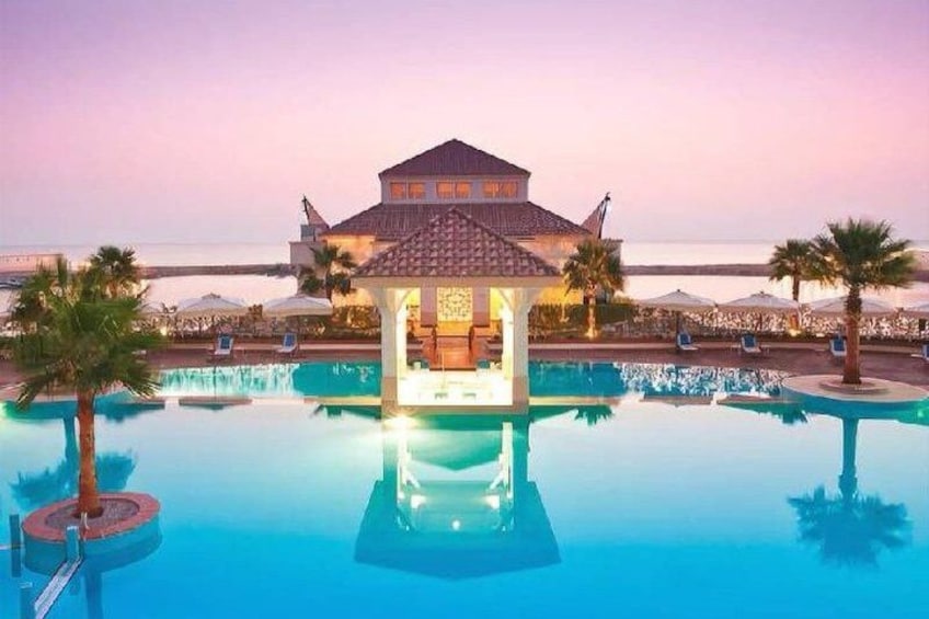 A swimming pool with a gazebo, palm trees, and a building in the background. 1
