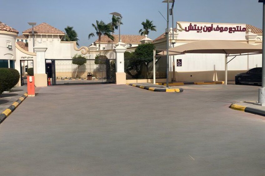 A gated entrance with a sign, palm trees, and a clear sky. 2
