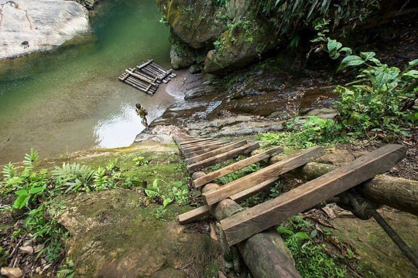 A wooden staircase leading down to a clear water body, surrounded by greenery and rocks. 2