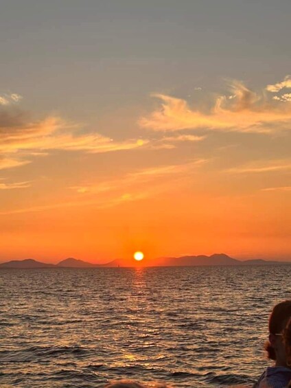 A sunset over the ocean with the sun near the horizon and a silhouette of mountains in the background. 5