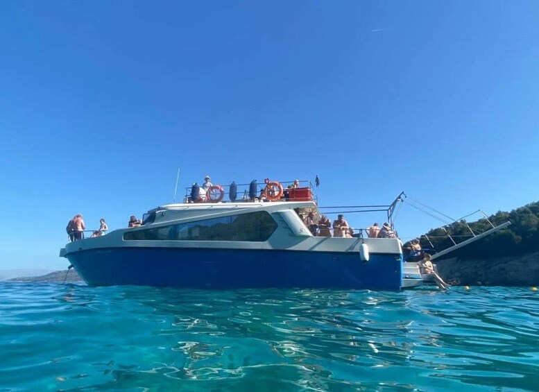 A boat with people on deck, surrounded by clear blue water. 3