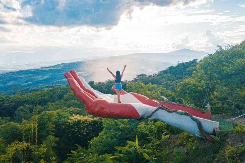 A person standing on a red and white slide with a mountainous landscape in the background. 2