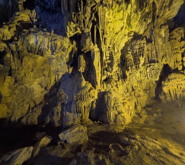 A cave with stalactites and stalagmites illuminated by artificial lighting. 2