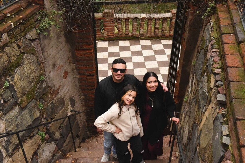 Una famiglia di tre persone percorre una stretta scala in pietra. 5