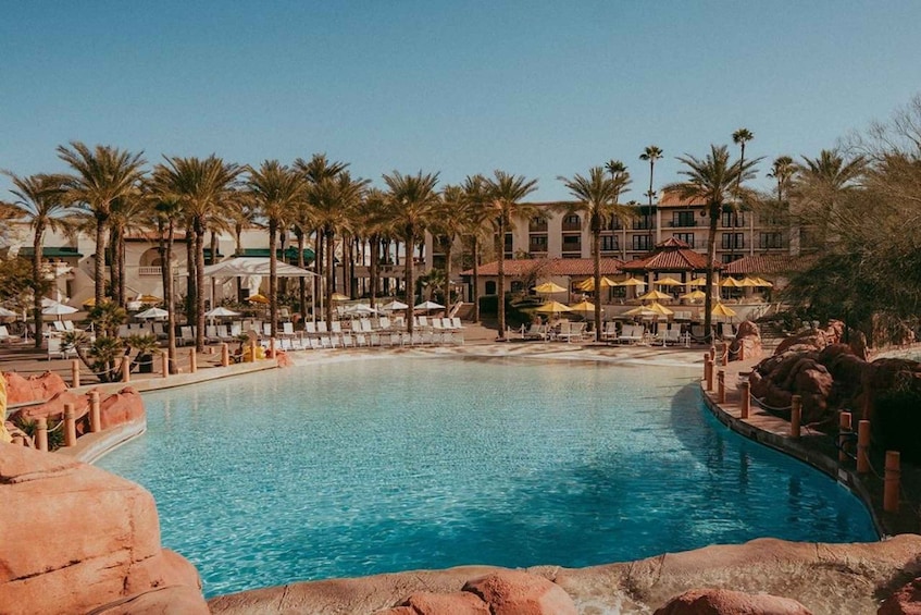 A swimming pool surrounded by palm trees and lounge chairs. 3