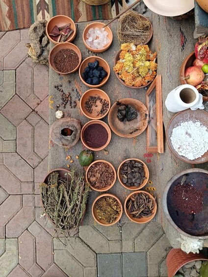 A variety of dried herbs and spices arranged in terracotta bowls on a patterned mat. 2
