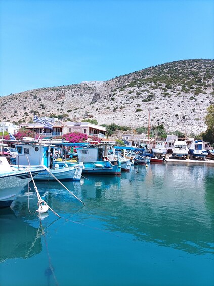 Un puerto con barcos, un edificio con un letrero y una ladera rocosa al fondo. 3