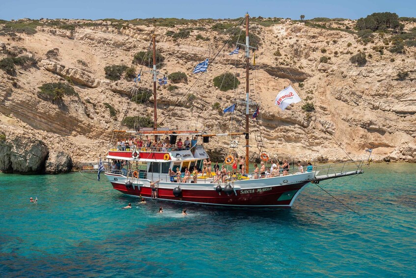 Un barco llamado 'Santa Maria' fondeado cerca de una costa rocosa con agua turquesa cristalina. 1