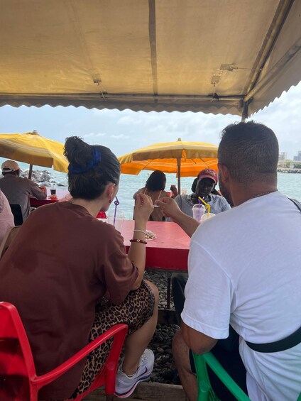 People seated at tables under umbrellas by the water. 3