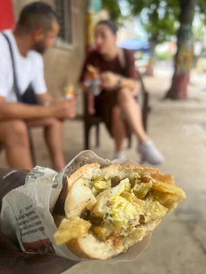 A person holding a sandwich with visible fillings. 5