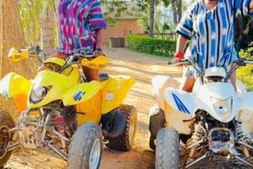 Two people on yellow off-road vehicles on a dirt path. 1