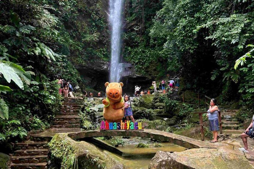 A waterfall, a bear statue, and a stone bridge in a forest. 1