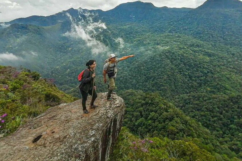 Two hikers on a rocky outcrop with a mountainous landscape in the background. 4
