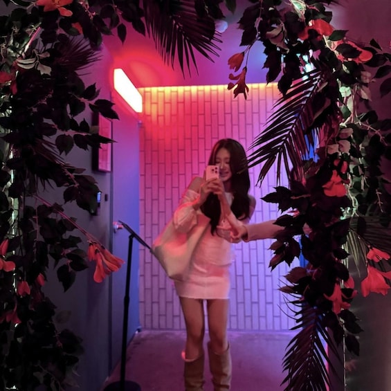A person taking a selfie in a room with a brick wall and artificial plants. 5