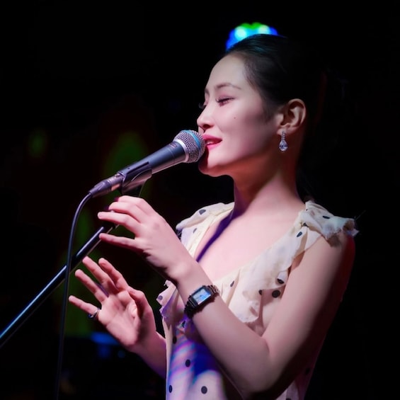 A person singing into a microphone with a blurred background. 1