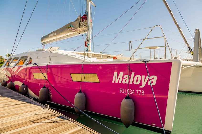 A pink and white yacht named Maloya docked at a marina. 2