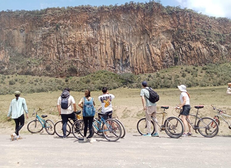 Un gruppo di persone in piedi con biciclette di fronte a un'imponente scogliera rocciosa. 2