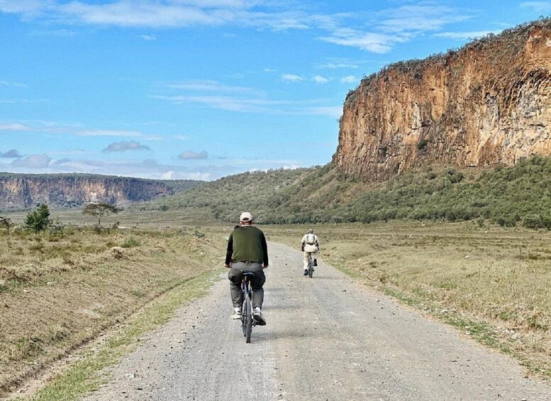Due ciclisti su una strada sterrata con una scogliera sullo sfondo. 1
