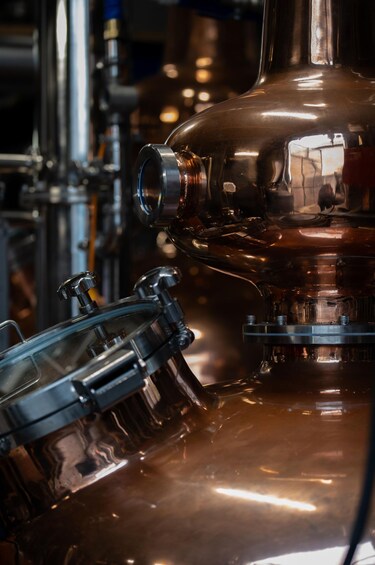 A copper distillation apparatus with a glass funnel and metal fittings. 1