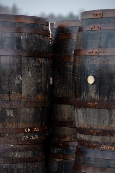 A stack of wooden barrels with metal bands and rivets. 2