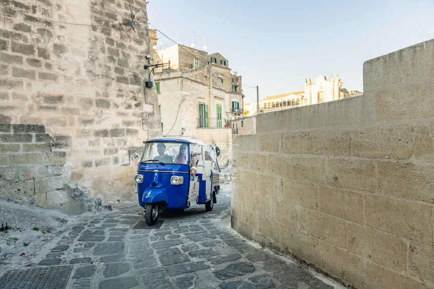 A narrow cobblestone street with a blue three-wheeled vehicle parked on the right side. 3