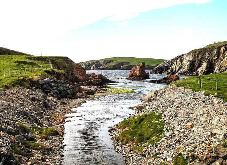 A rocky coastal landscape with a narrow stream flowing through it. 3