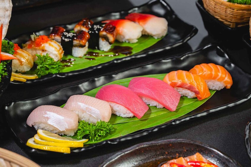 A variety of sushi on black plates with a green leaf garnish. 2