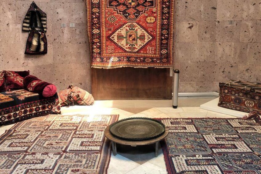 A room with a patterned rug, a wooden chest, and a hanging tapestry. 3
