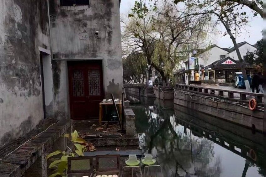 A traditional building with a red door, a narrow waterway, and a wooden bridge. 3