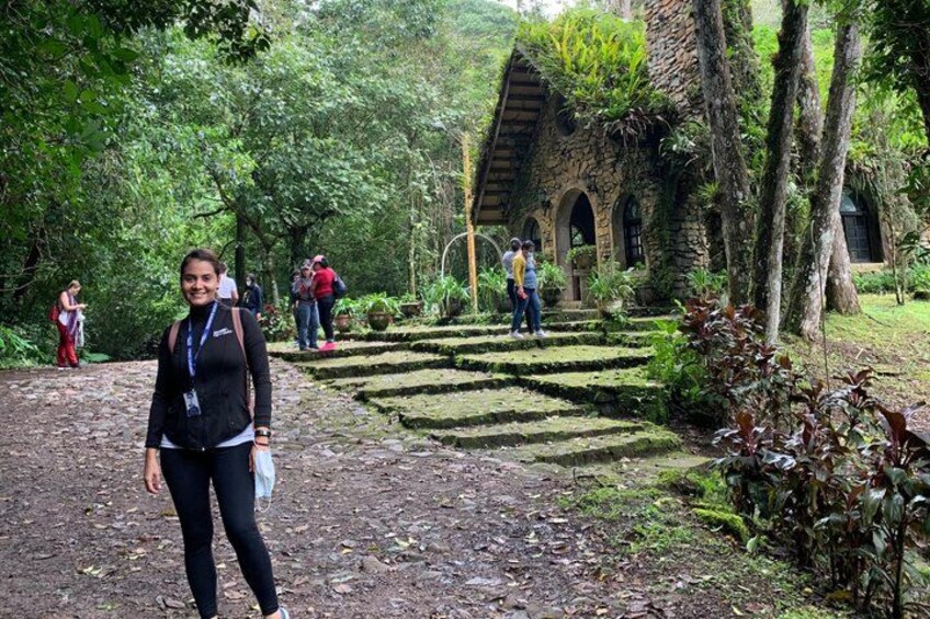 A woman standing in a lush garden with a stone building in the background. 5