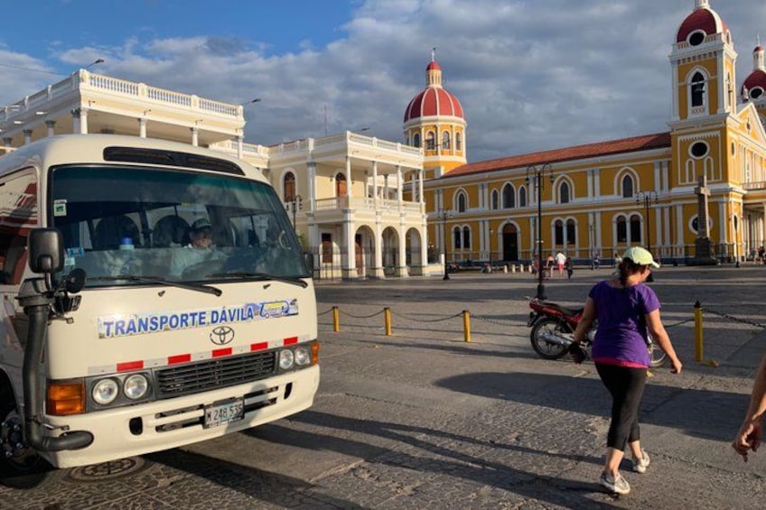 A bus with 'TRANSPORTE DAVILA' on its front, a yellow building with red domes, and a person walking. 3